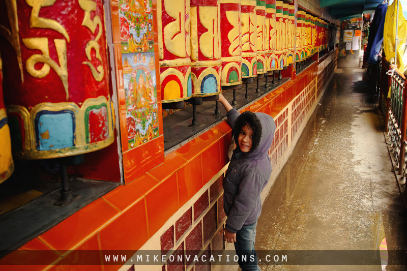child spinning prayer wheels in Buddhist temple Manali family travel activities Himalayas
